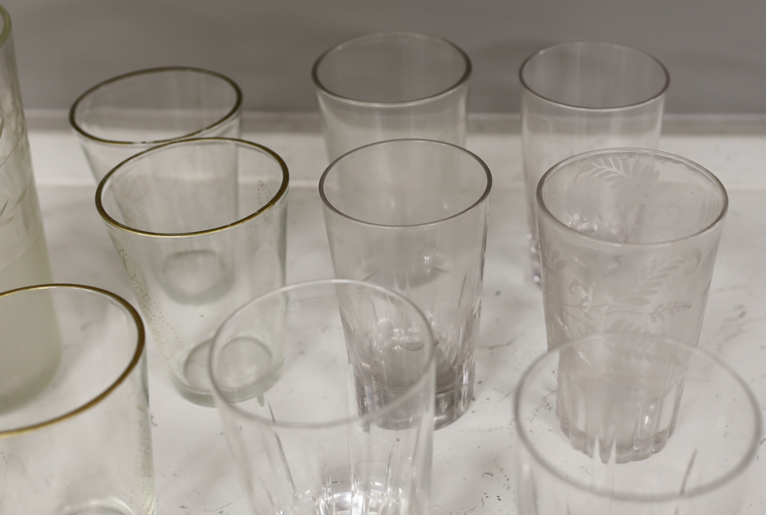 A collection of 19th and early 20th century drinking glasses, including beakers, some etched examples, half pint ale mug, an etched glass jug, etc., tallest 17cm (20)